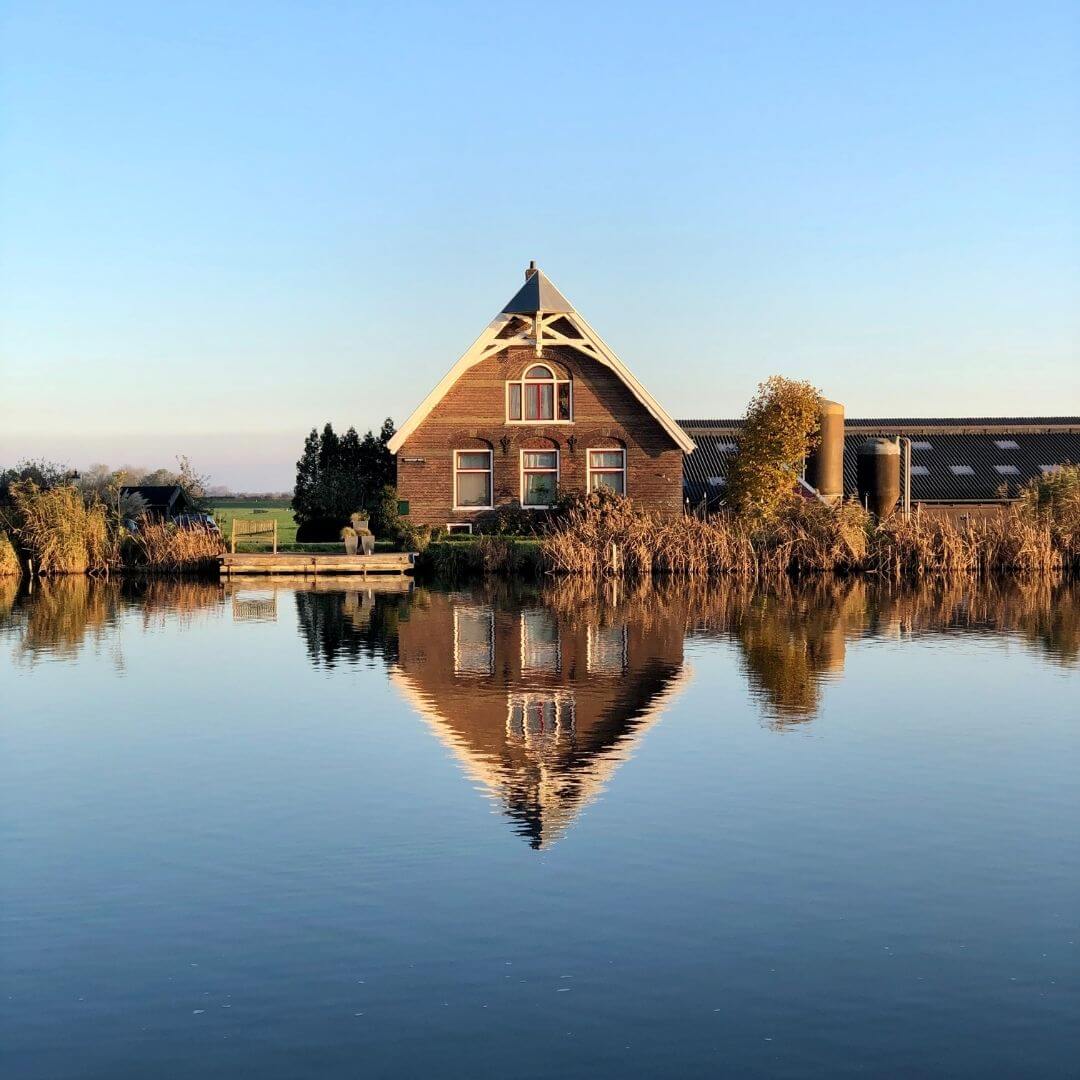 Een huis dat weerkaatst in het water van een meer, met een vredige en natuurlijke achtergrond.